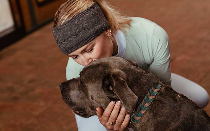 Frau mit Samshield Stirnband küsst Hund