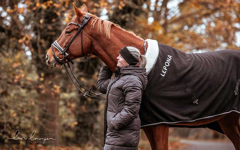 Reiterin mit Pferd im Herbstlaub