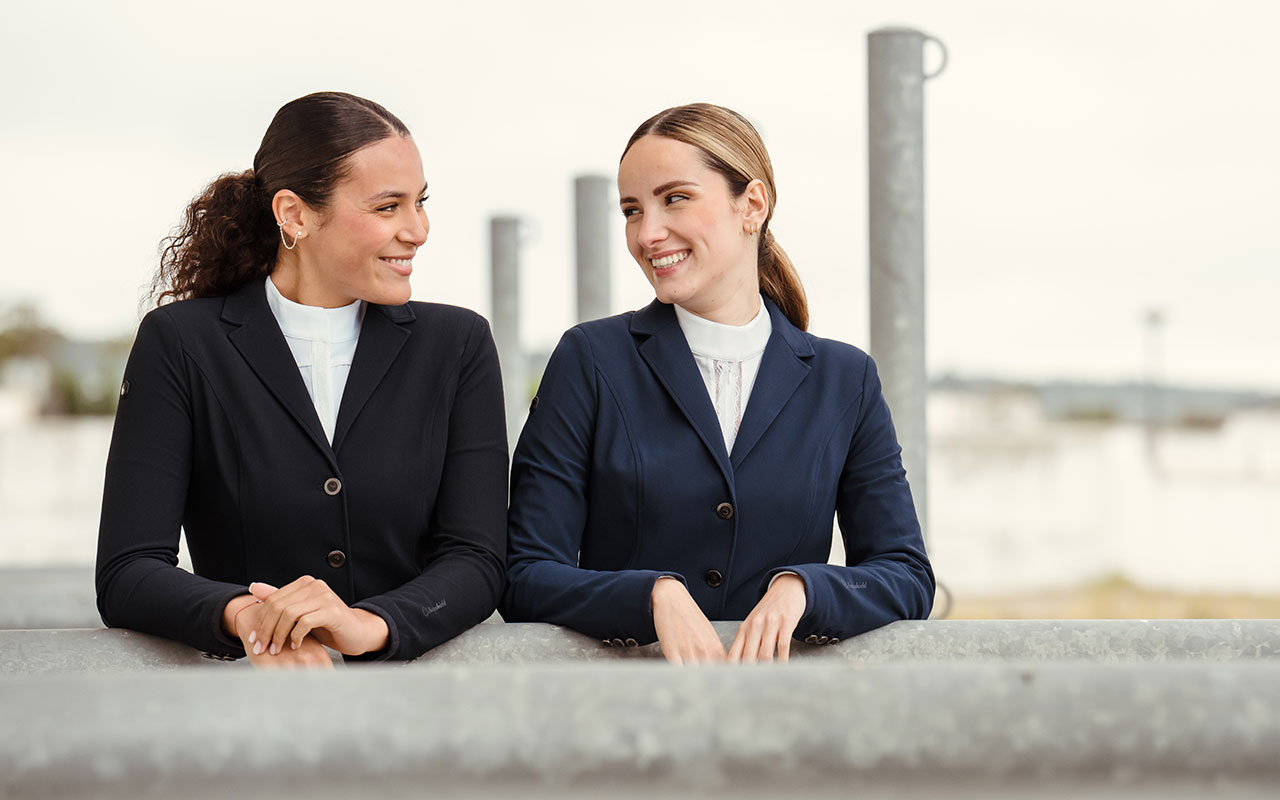 Zwei Frauen mit Turnierjacket lächeln sich an