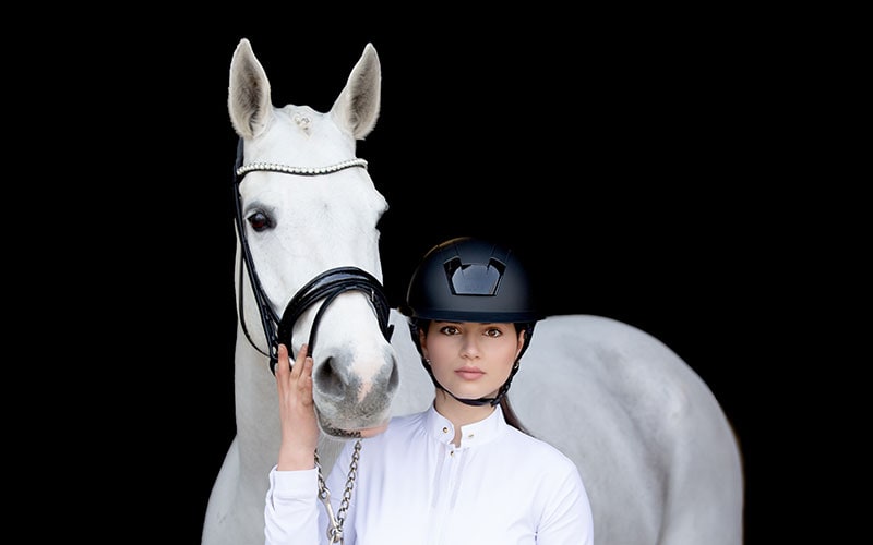 Frau mit Schimmel und schwarzem Kask Reithelm