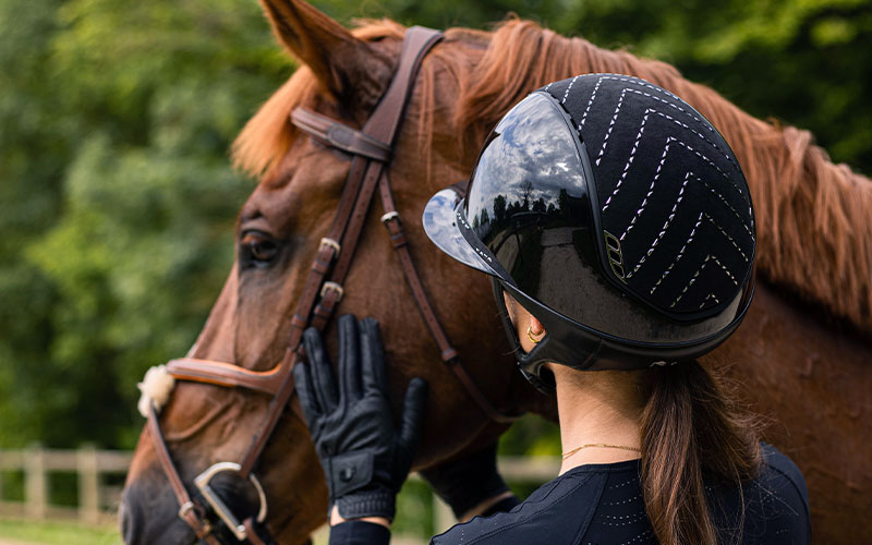 Frau von Hinten mit Pferd und Samshield Reithelm